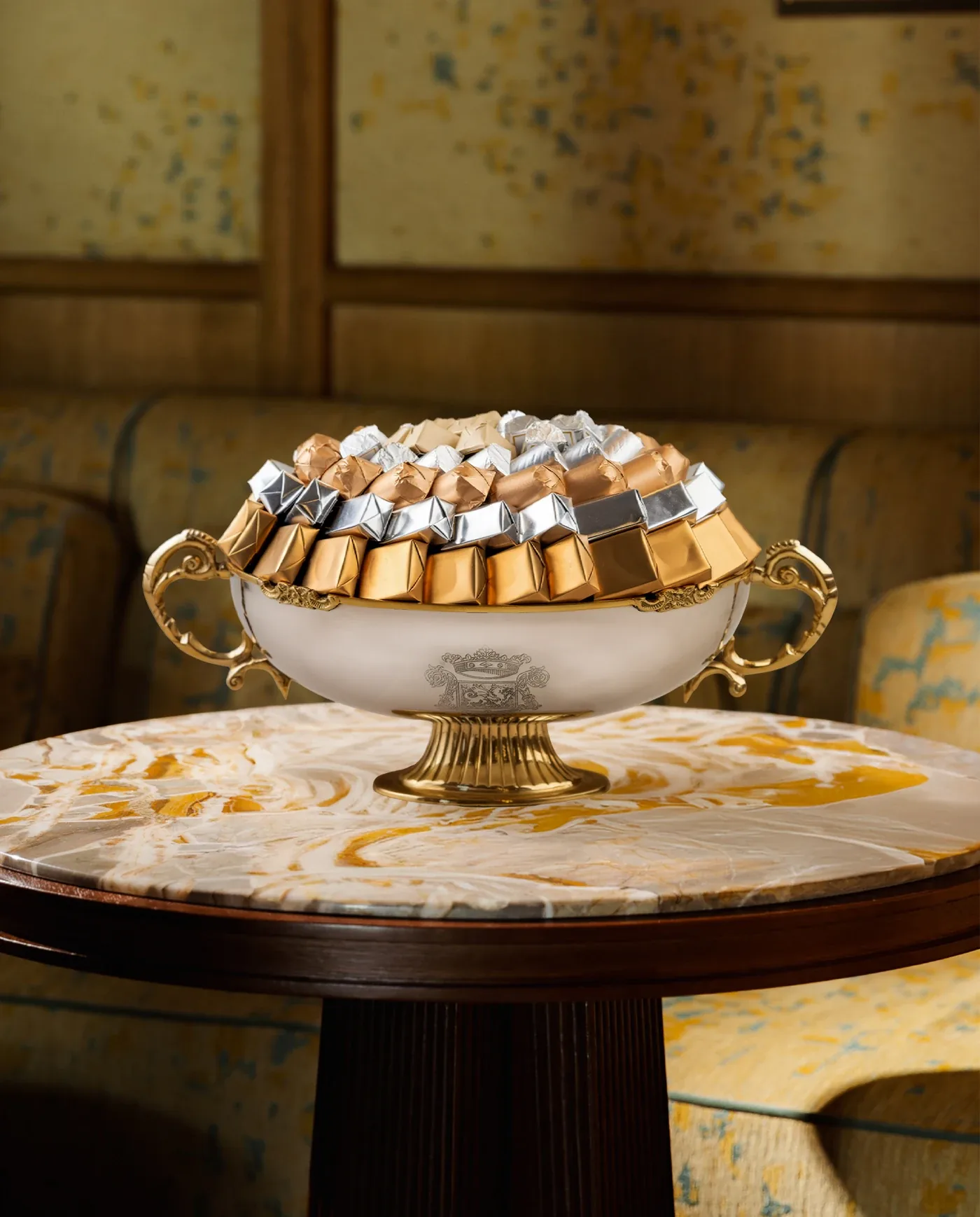 Coupe blanche à anses dorées garnie de chocolats or, argent et bronze