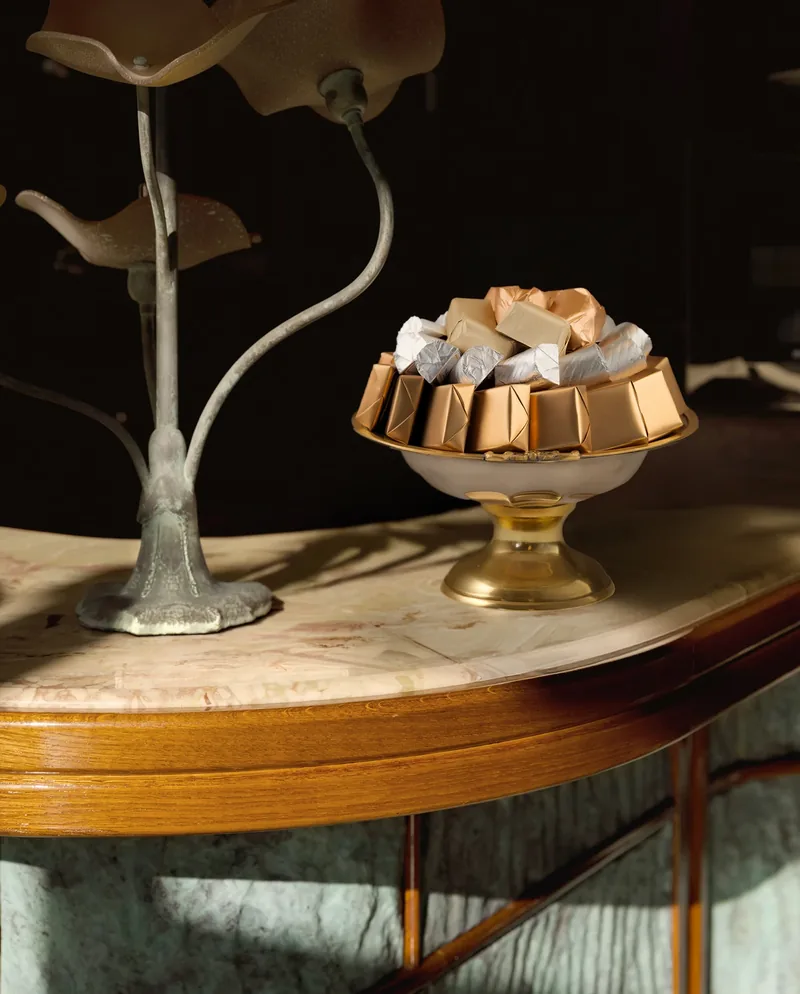 Petite coupe à pied doré garnie de chocolats sur une console en marbre