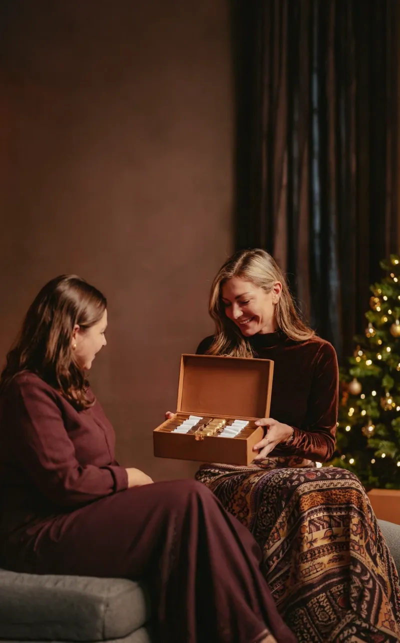 Une femme ouvre un coffret NAYA en cuir camel offert par une amie